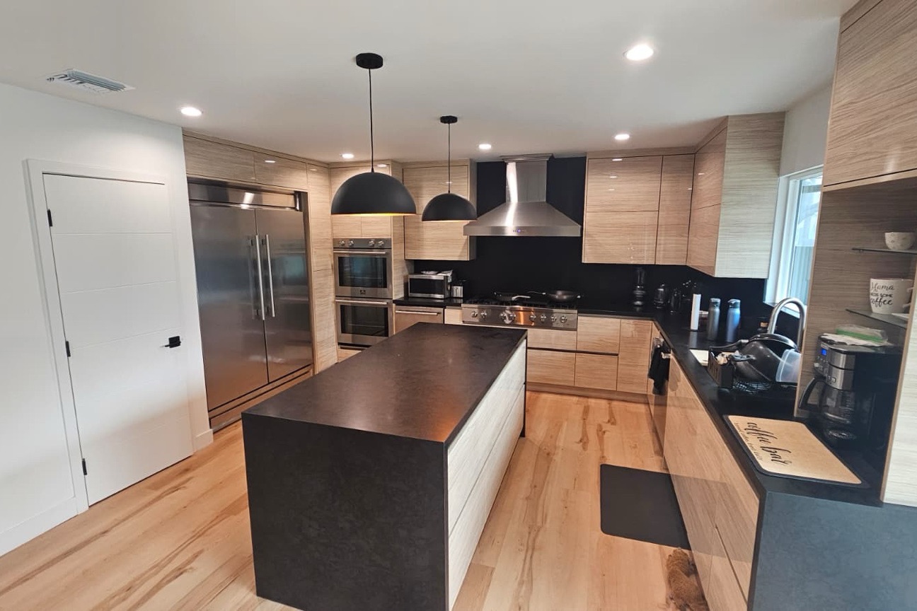 Westside kitchen remodel by Udi's Construction — light wood cabinetry, black waterfall island, stainless appliances